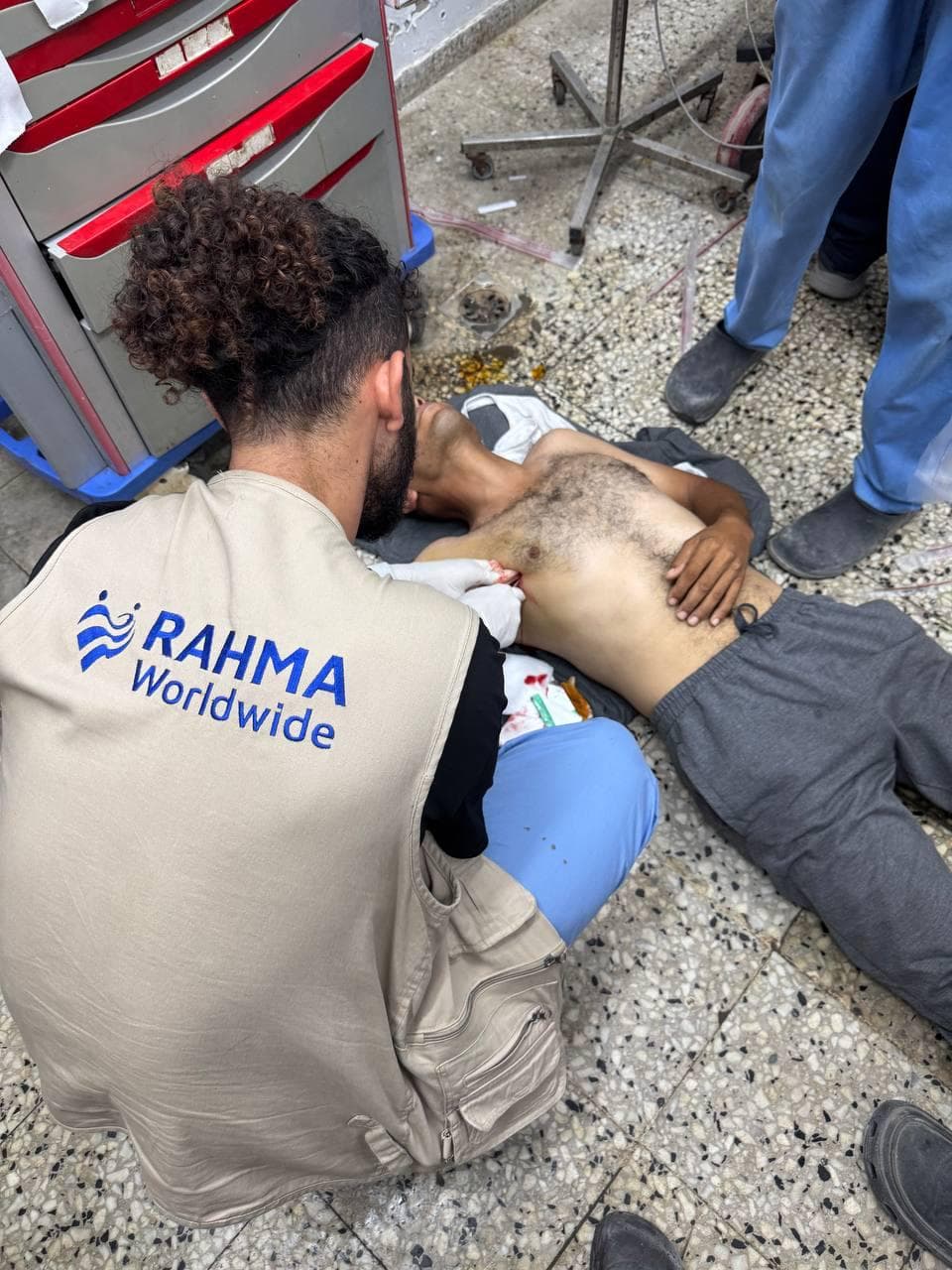 Volunteer kneeling beside a patient on a hospital floor