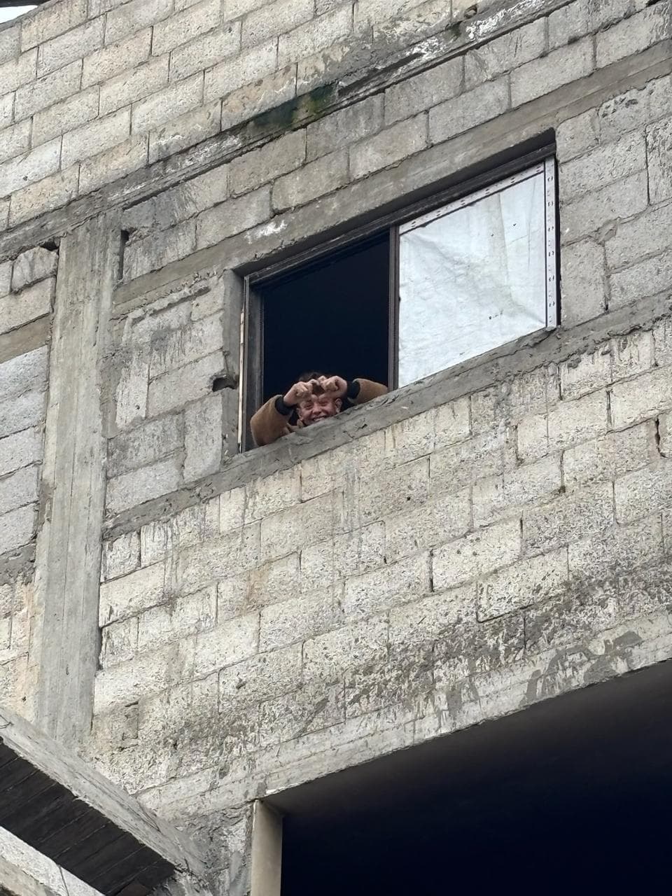 Person looking out of a window in a damaged building