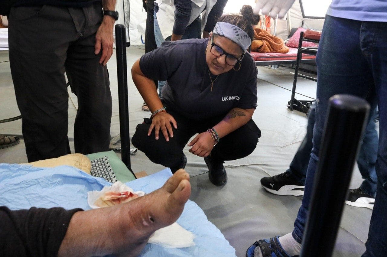 Volunteer crouching to examine a patient's foot